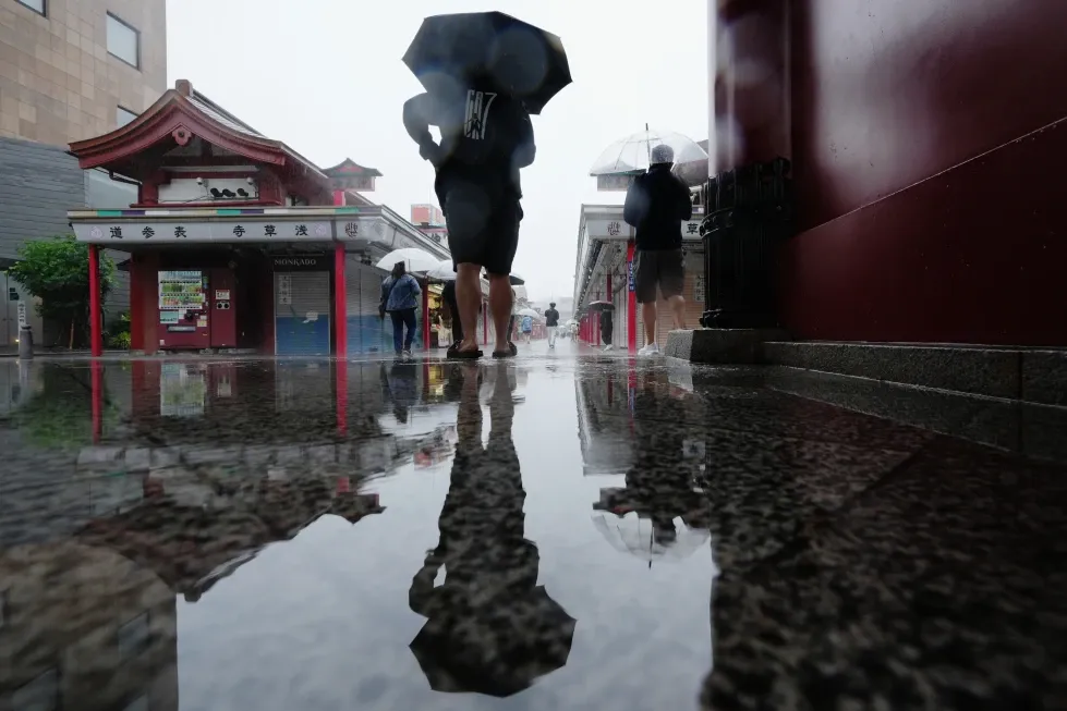 Un hombre se detiene para resguardarse de la lluvia en Tokio, el miércoles 3 de junio de 2026. (AP Foto/Hiro Komae)