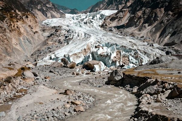 Glaciar en Nepal con un río que fluye, representando el impacto del cambio climático en la región.