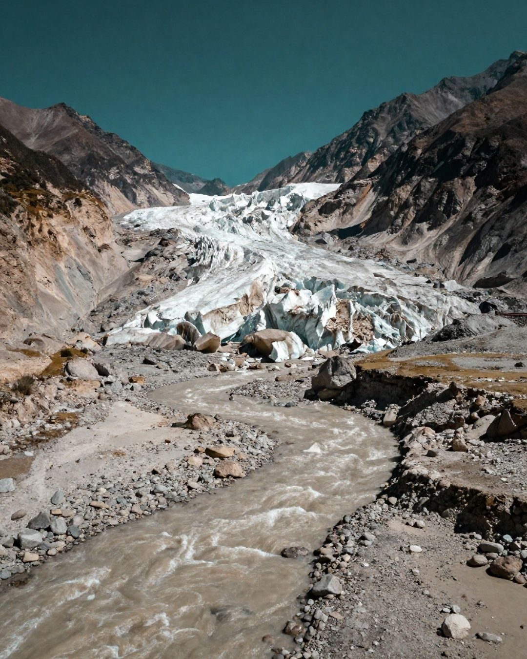 Glaciar en Nepal con un río que fluye, representando el impacto del cambio climático en la región.