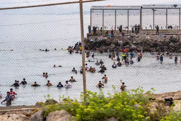 Migrantes se concentran junto al espigón fronterizo de Ceuta tras la difusión de rumores en redes sociales sobre una supuesta apertura de la frontera.