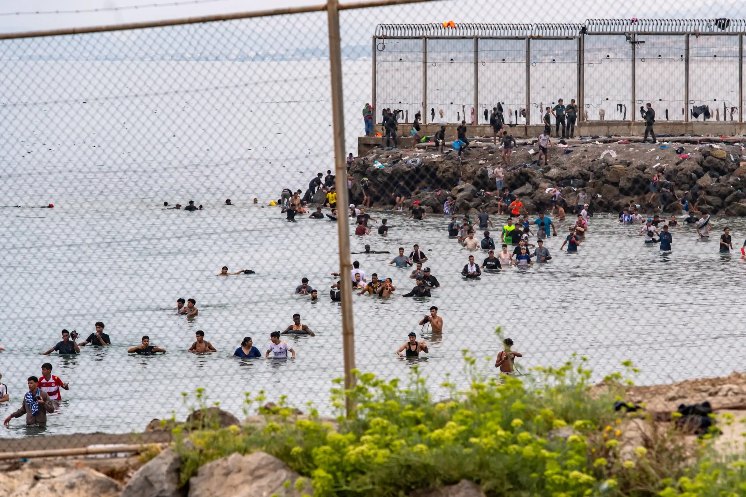 Migrantes se concentran junto al espigón fronterizo de Ceuta tras la difusión de rumores en redes sociales sobre una supuesta apertura de la frontera.
