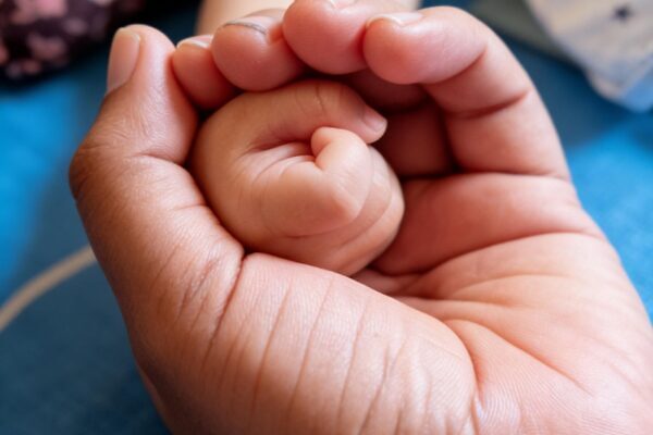 Un primer plano conmovedor de la mano de un bebé sostenida por uno de sus padres, que simboliza el amor y el cuidado.