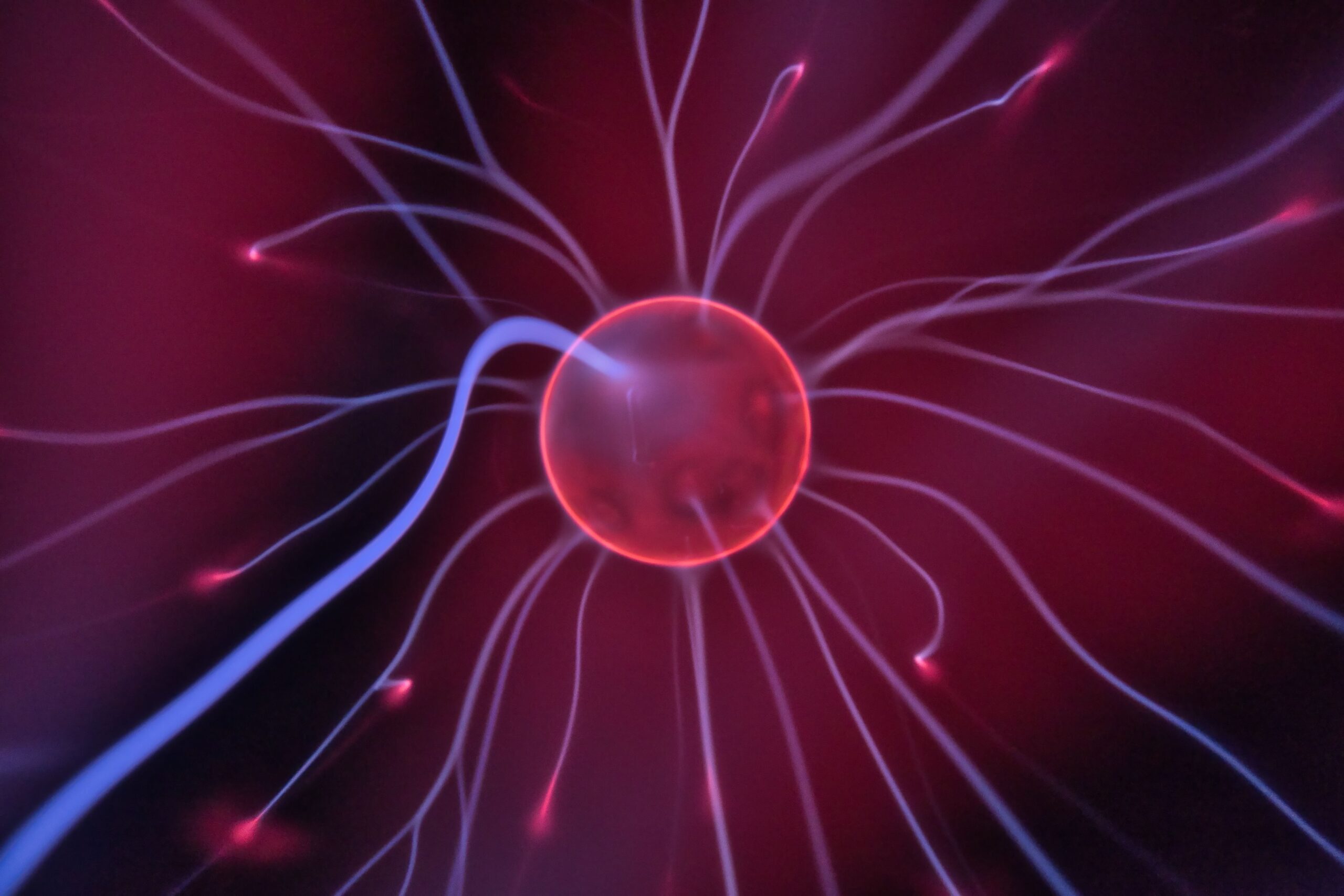 Primer plano de una bola de plasma brillante con corrientes eléctricas coloridas que se extienden hacia afuera.